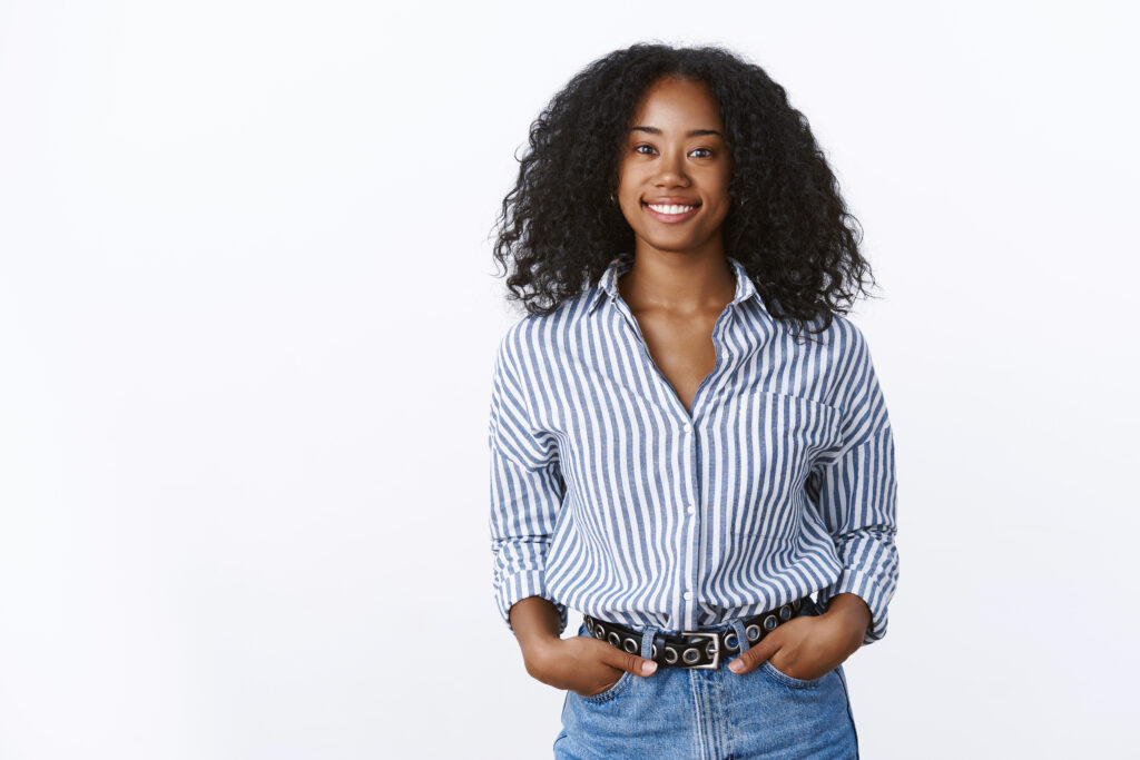 charismatic cheerful attractive african american woman curly haircut wearing shirt holding hands pockets confident outgoing smiling, talking pleasant conversation, feeling self assured relaxed